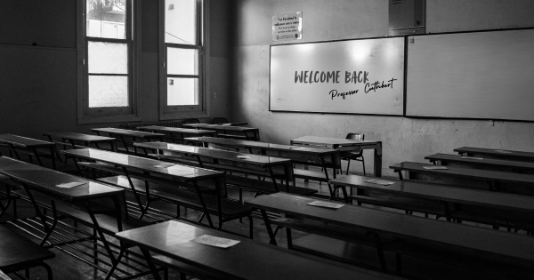 A photo of a classroom with "Welcome Back, Professor Cuthbert" on the board.